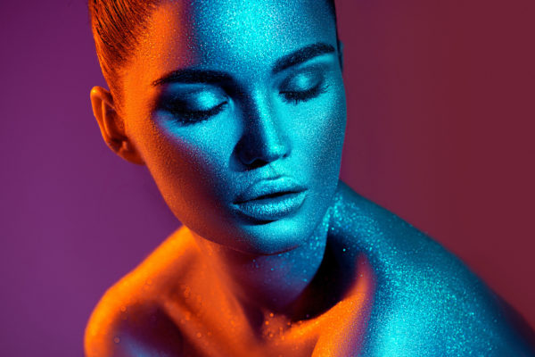 Fashion model woman in colorful bright sparkles and neon lights